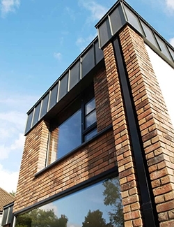 Close-up of a contemporary brick Architect-designed house extension in Sandymount, Dublin with large windows and a distinctive black roof, showcasing a juxtaposition of textures and materials