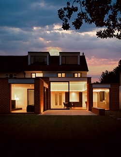 Twilight view of a house reconstruction project in Malahide, Dublin with warm interior lighting visible through large windows