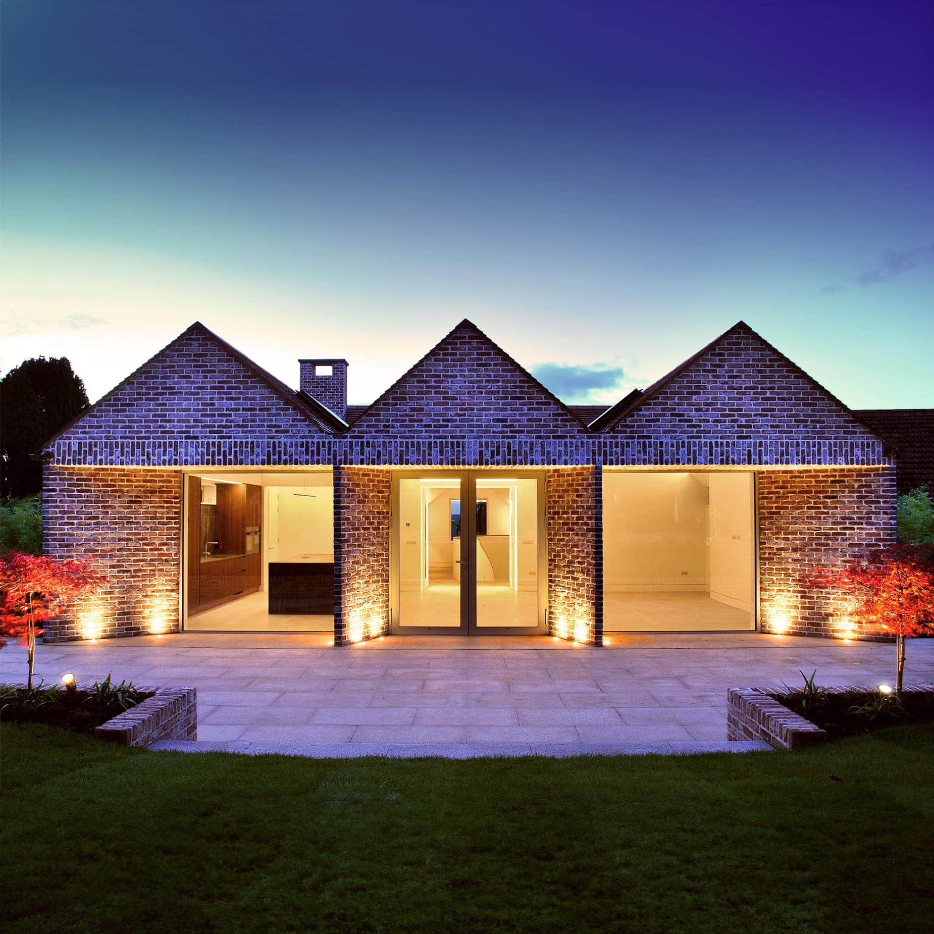 Gabled elevation of a South Dublin brick house at dusk, lit by exterior lights